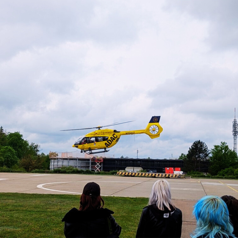 Schülerinnen und Schüler der Laura-Schradin-Schule sehen einem landenen Notfallhubschrauber zu.
